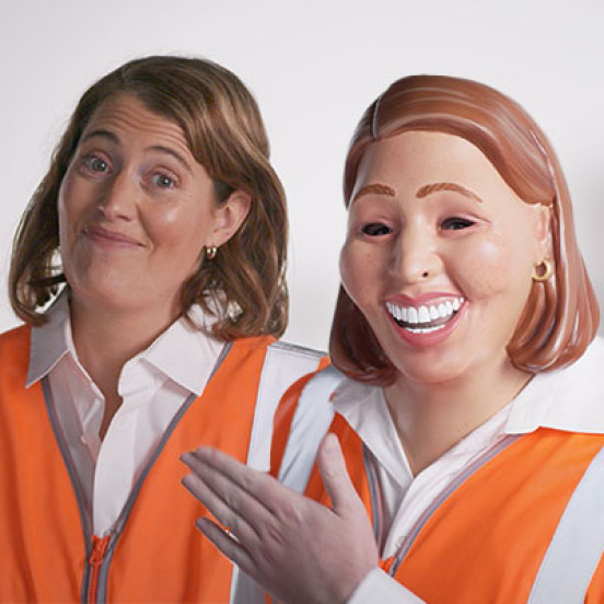 Photo of a woman in a high visibility vest with another woman next to her that is dressed the same but wearing a mask