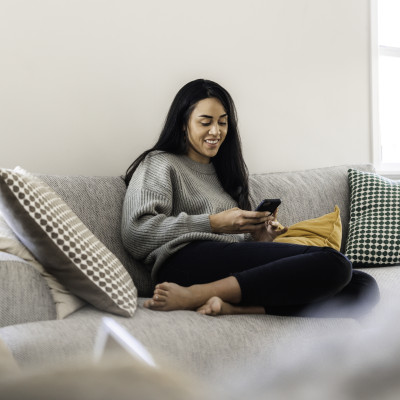 Young woman sitting on the sofa on her phone