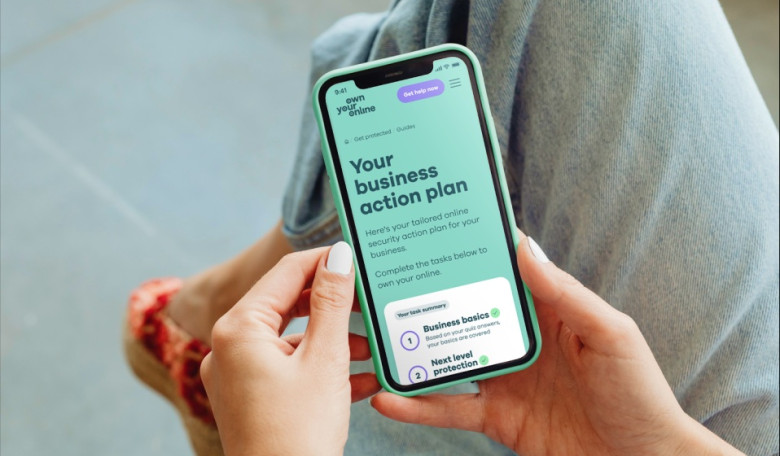 Photo of a woman's hands holding a mobile phone with webpage showing the words Your business action plan.